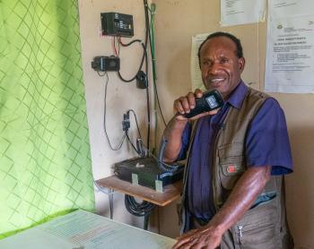 A man holds a radio mouthpiece and smiles