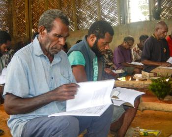 A man sits and reads the Bible and a workbook
