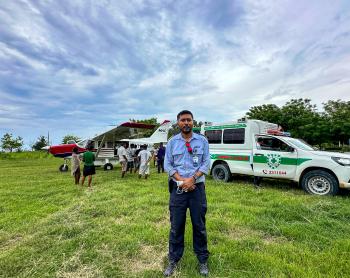A pilot in front of a small plane and ambulance