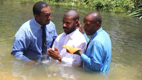 MAF Technologies representative, Nicholas Jowapo assisting in baptising a new believer in the water.