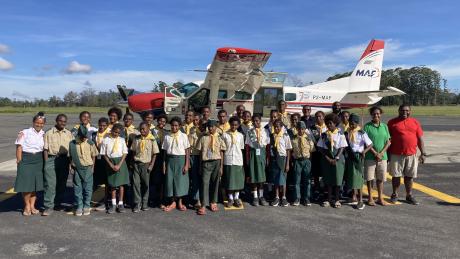 Balimo Pathfinders group standing in front of MAF plane, awaiting flights home to Balimo.