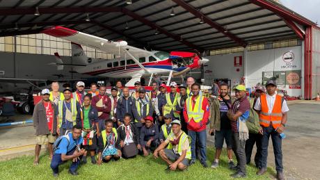 group photo of Mougulu grade 12 students in front of MAF's hangar at Mt Hagen with the floatplane in the background