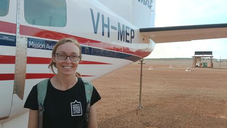 Public health worker standing in front of aircraft on Tarmac