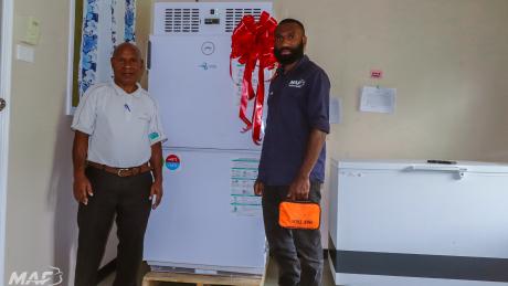 MAF Technologies technician Steven Zato guiding a health worker on the safe use of a solar-powered vaccine fridge.