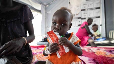 12-month-old Nyalam enjoys a sachet of ready-to-use therapeutic food (RUTF) at the Medair stabilization center in Akobo, marking a powerful milestone in her journey to full recovery from severe acute malnutrition