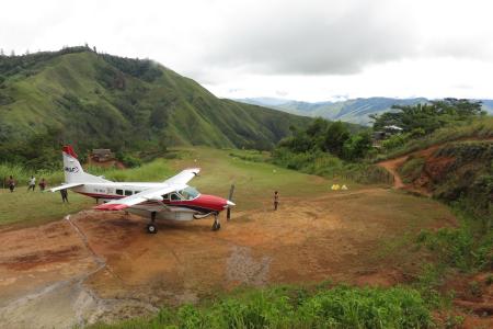 One MAF plane situated on the top of the Owena Airstrip with mountains in the background