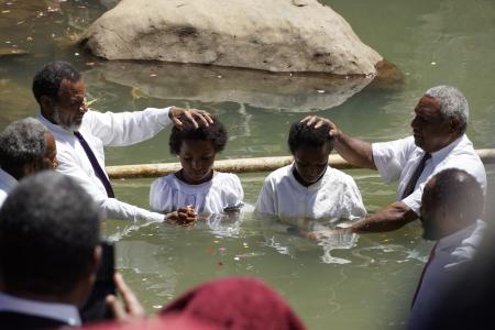 Two youths being baptised in Rum
