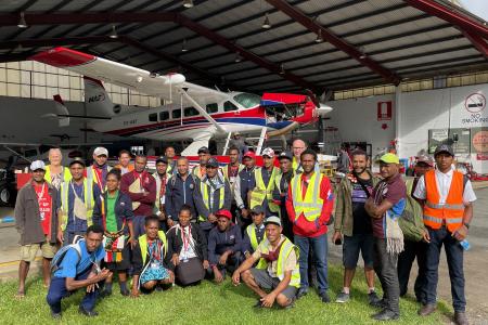 group photo of Mougulu grade 12 students in front of MAF's hangar at Mt Hagen with the floatplane in the background
