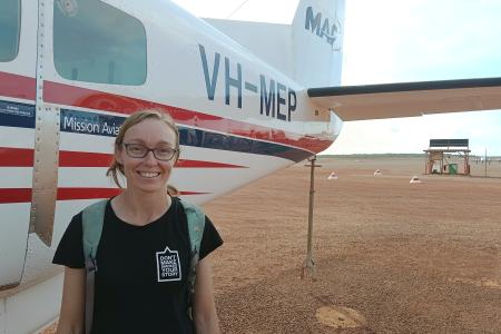 Public health worker standing in front of aircraft on Tarmac