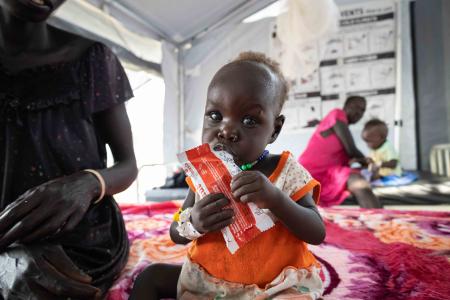12-month-old Nyalam enjoys a sachet of ready-to-use therapeutic food (RUTF) at the Medair stabilization center in Akobo, marking a powerful milestone in her journey to full recovery from severe acute malnutrition