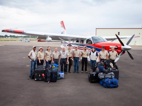 A disaster response team pose in front of an aeroplane