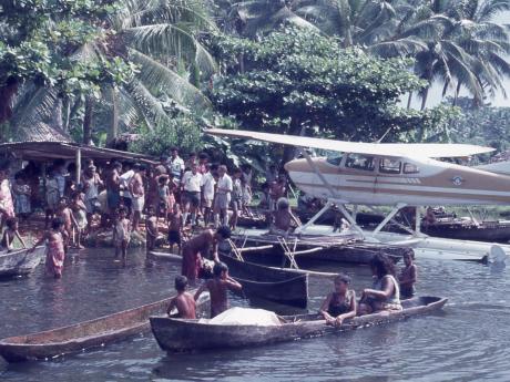 A floatplane on the water ashore next to canoes