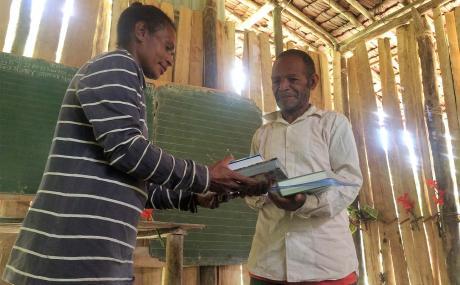 Joyce presenting Bibles to the pastor at Sitiman
