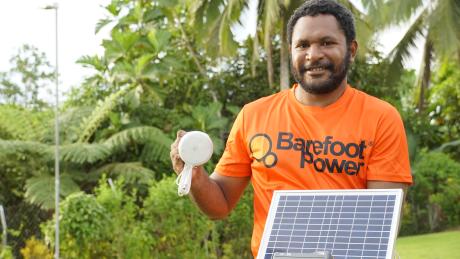 Hobert Asari showing the solar panel and light as part of the Barefoot Solar home kit installation