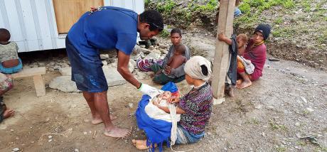 Yanis giving medicine to a baby