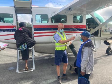 MAF pilot tests a passenger's temperature before boarding a MAF flight