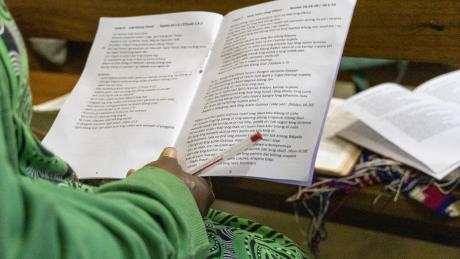 women holding an open booklet with notes of the teaching