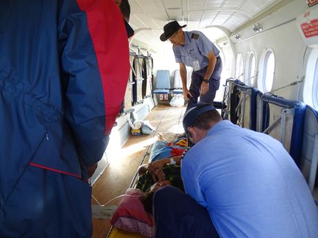 the pilots securing the stretcher on which Osa lays, to the cabin of the Twin Otter