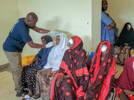 An ophthalmologist providing post-surgical care to an elderly woman.