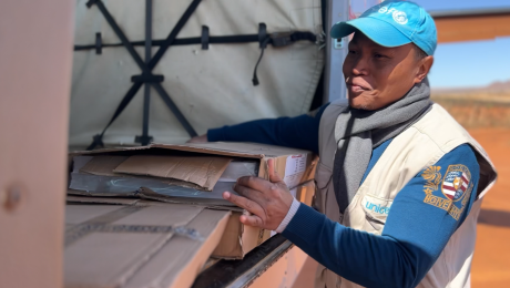 UNICEF worker carrying vaccine supplies from MAF plane