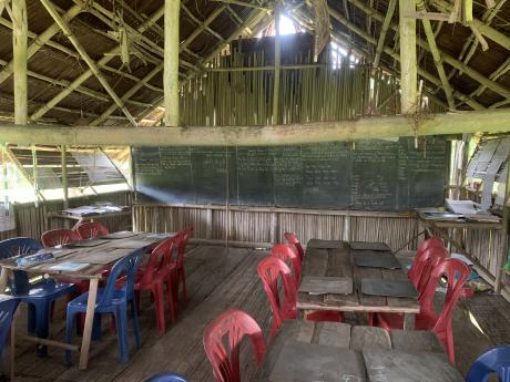A basic classroom along the Sepik River, with student tables and a large chalkboard.