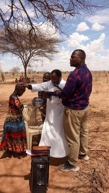 Pastor Robinson praying for a young girl who found salvation in Chidudu.