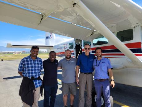 Survey team for the float plane project - Satish Moka, Samuel Okposin, Terry Fahey, Chad Tilley and Timon Kundig standing beside MAF plane.