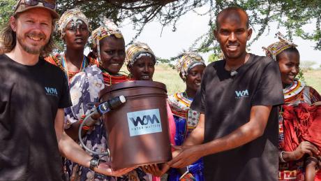 Meshack Gayere, pictured on the left, receives a bucket equipped with a water filter in Loglogo