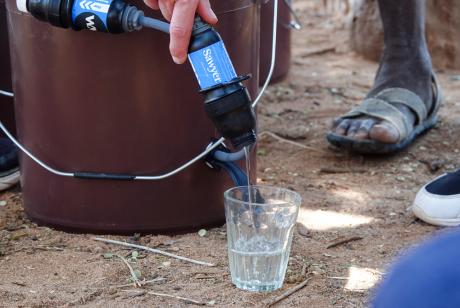 A member of Water Matters pours out clean purified water into a glass after the purification process during a demonstration