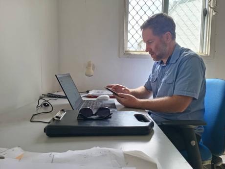 A man works on his phone at his desk