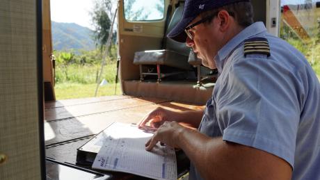 Tim Neufeld doing paperwork for the next flight using the cabin floor as a desk