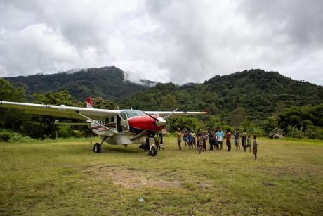 An aeroplane on an airstrip with villagers