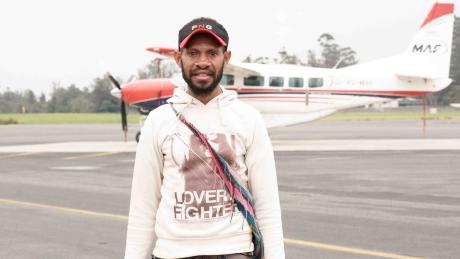 Pastor Perry Ken standing in front of a plane