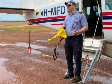 Pilot standing on Cessna C208 steps.