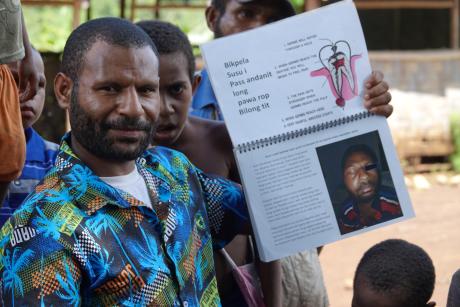 Kenneth Makandea standing with a book about dental health