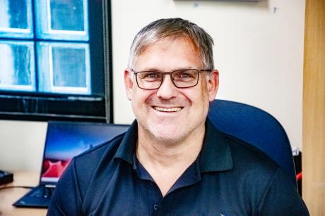 Man at office desk smiling at camera