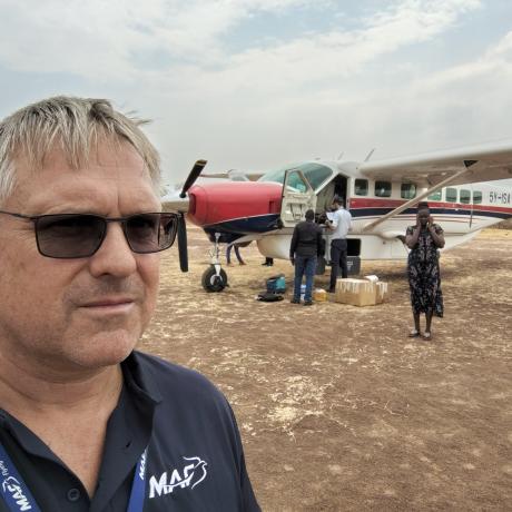 Man at airstrip with aircraft in background