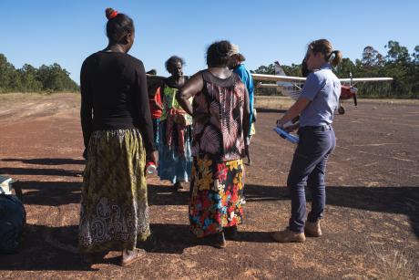 Peopole standing on red dirt airstrip