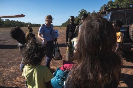 People standing on red dirt airstrip