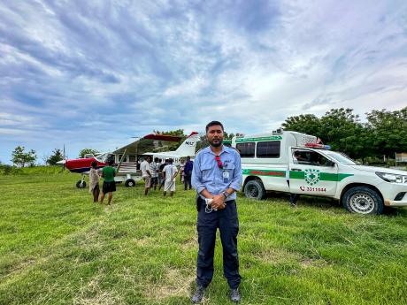 A pilot in front of a small plane and ambulance