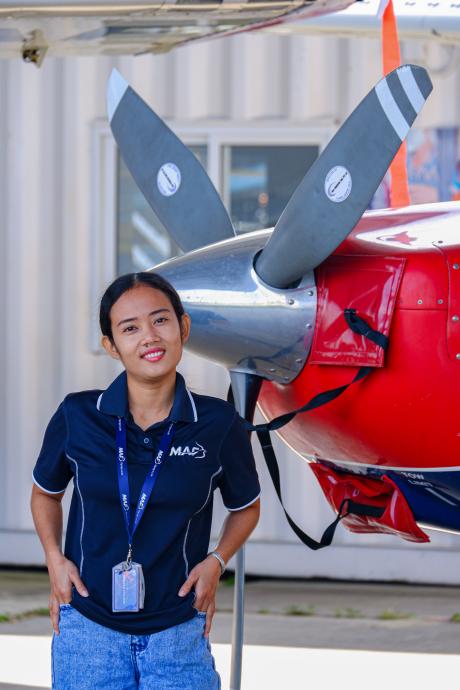 A woman stands in front of a small aeroplane