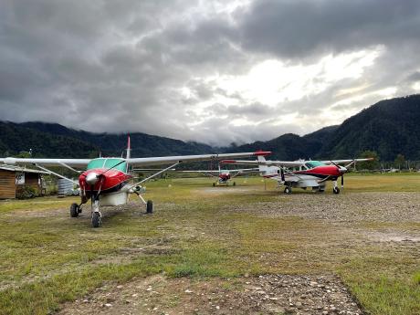Three aeroplanes parked on a remote mountain airstrip