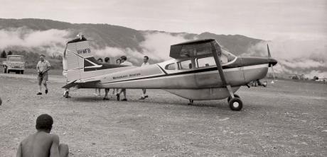 a tribesman looks at a plane on an airstrip 