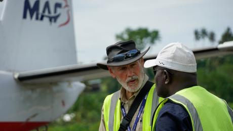 A man talking to another man near a plane