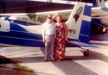 A couple stand in front of a small plane