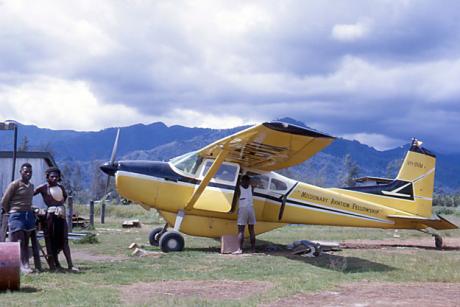 A plane on an airstrip with local people watching