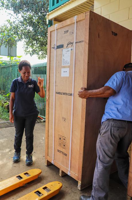 Jovina Kerowa and colleague Johnson Irarue stand beside a solar-powered vaccine refrigerator awaiting transport to a remote health centre in Papua New Guinea.