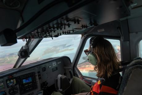 Woamn wearing headphones seated in aircraft cockpit