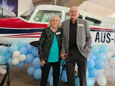 Two people smile with a small plane