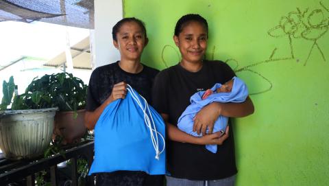 a mum and aunt with a baby and a care package bag